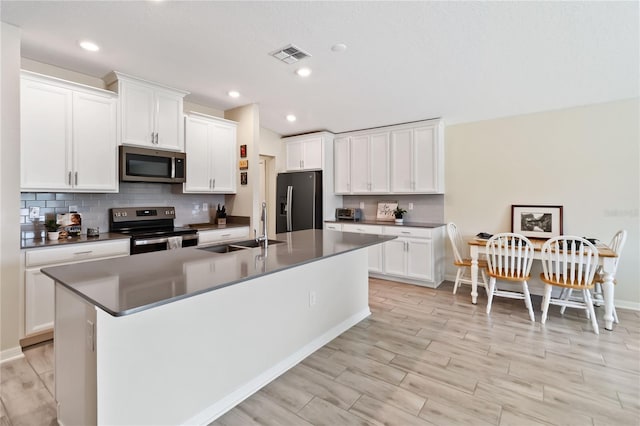 5347 Travertine St, Mount Dora, FL 32757 - kitchen featuring stainless steel appliances, a sink, backsplash, a kitchen island with sink, and white cabinetry