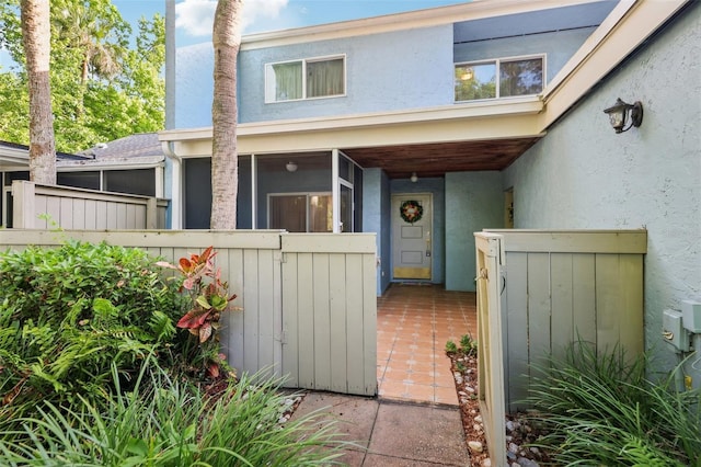 view of exterior entry featuring fence and stucco siding
