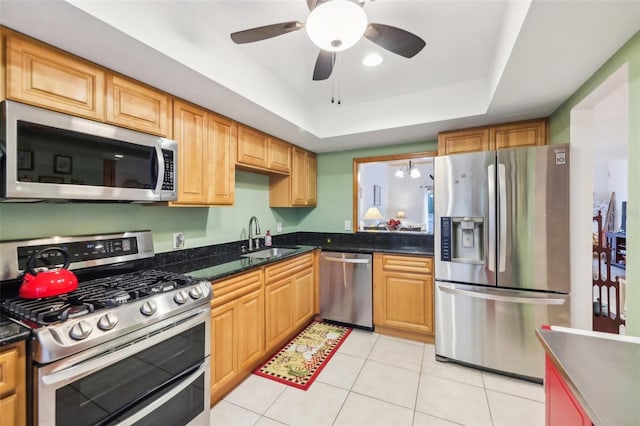 kitchen with ceiling fan, appliances with stainless steel finishes, a sink, light tile patterned floors, and a raised ceiling