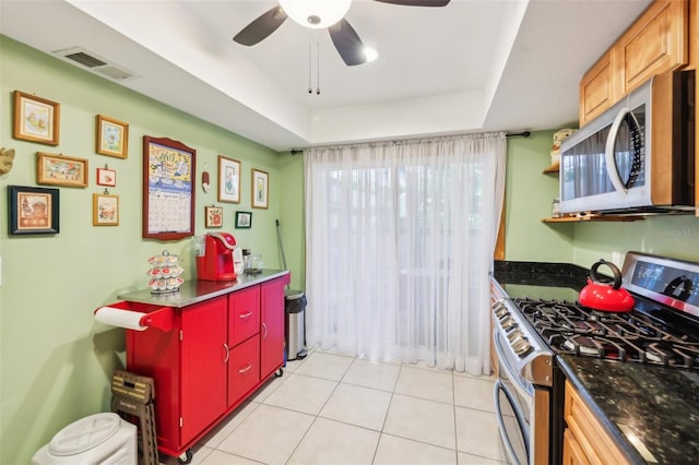 kitchen with a ceiling fan, visible vents, dark countertops, light tile patterned floors, and stainless steel appliances