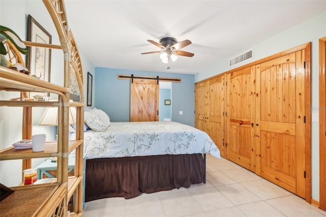 bedroom featuring light tile patterned flooring, visible vents, and a barn door