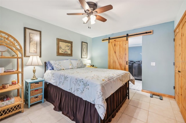 bedroom featuring independent washer and dryer, light tile patterned flooring, a ceiling fan, and a barn door