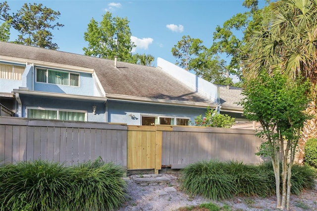 exterior space with fence, stucco siding, and roof with shingles
