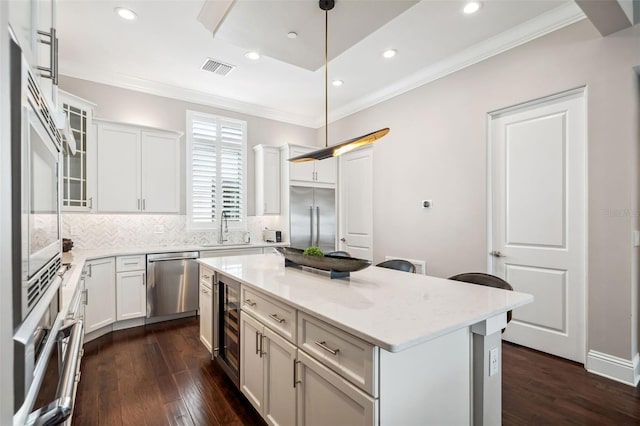kitchen with a kitchen island, backsplash, a sink, beverage cooler, and stainless steel appliances
