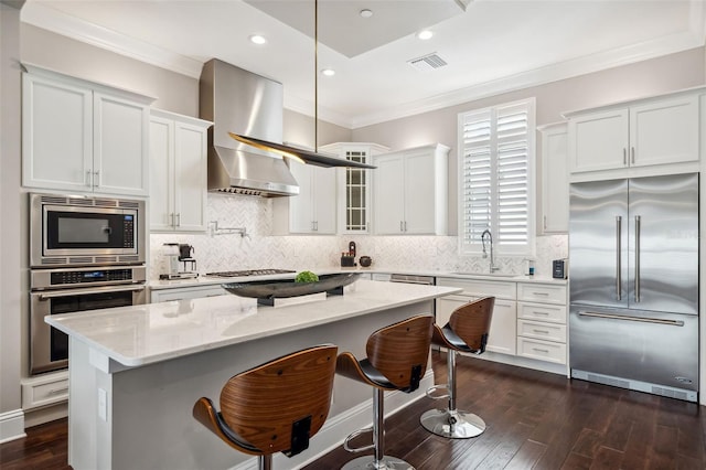 kitchen with crown molding, built in appliances, a kitchen island, dark wood-type flooring, and white cabinetry