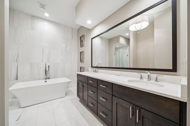 bathroom with a sink, a freestanding tub, visible vents, and marble finish floor