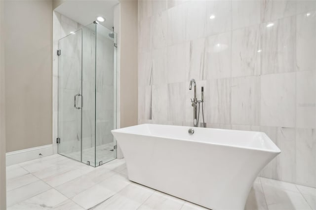 full bath featuring a freestanding tub, tile walls, and a marble finish shower