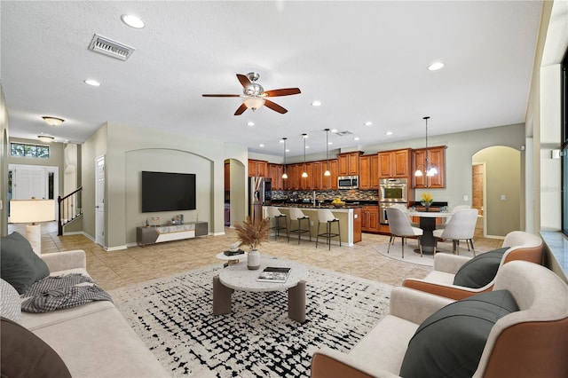 living room featuring ceiling fan, arched walkways, recessed lighting, baseboards, and visible vents