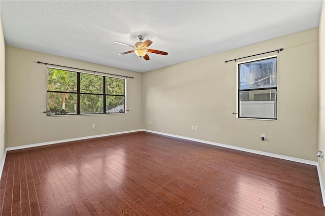 empty room featuring baseboards, a ceiling fan, dark wood-style flooring, and a textured ceiling