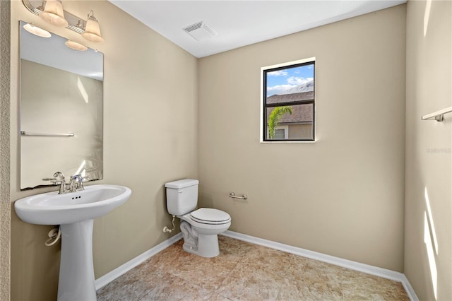 bathroom with a sink, baseboards, toilet, and visible vents