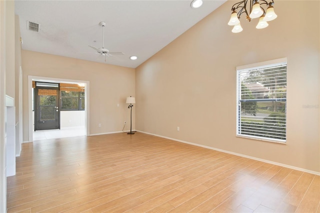 spare room with baseboards, vaulted ceiling, light wood-style flooring, and ceiling fan with notable chandelier