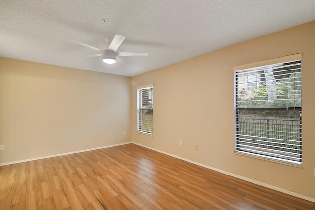 empty room with a textured ceiling, baseboards, a ceiling fan, and wood finished floors