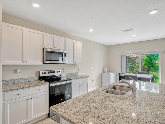 3033 Beau Loop, Tavares, FL 32778 - kitchen with white cabinets, stainless steel appliances, visible vents, and a sink