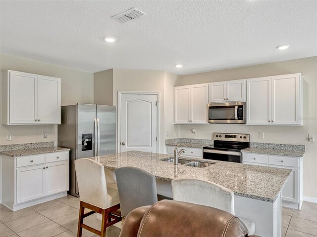 3033 Beau Loop, Tavares, FL 32778 - kitchen with visible vents, white cabinetry, a sink, appliances with stainless steel finishes, and light tile patterned floors