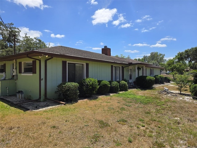 view of side of property featuring a yard and a chimney