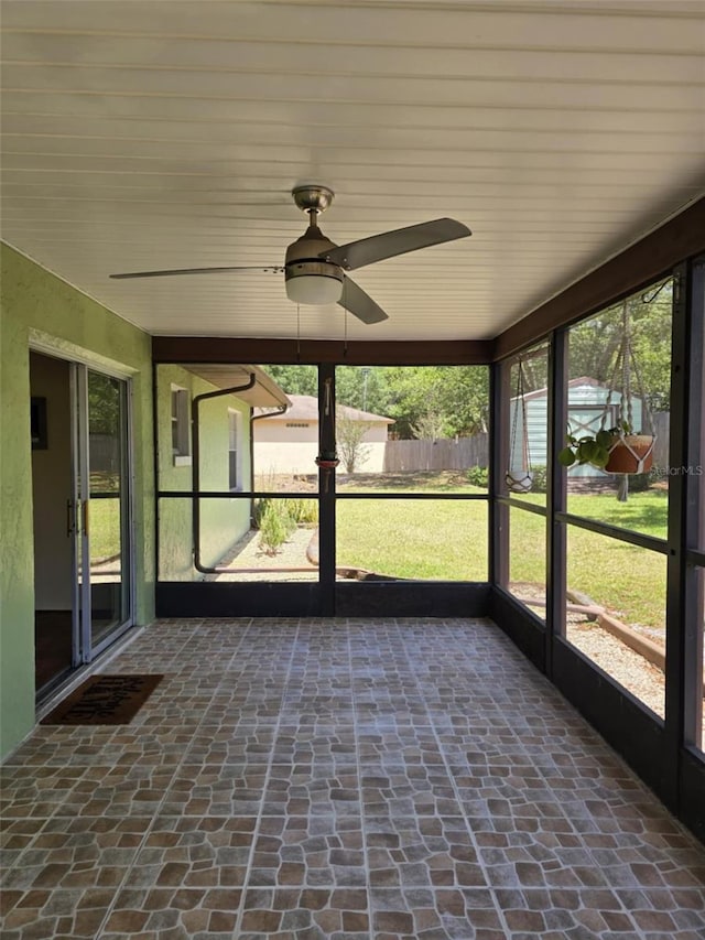 unfurnished sunroom with plenty of natural light and a ceiling fan