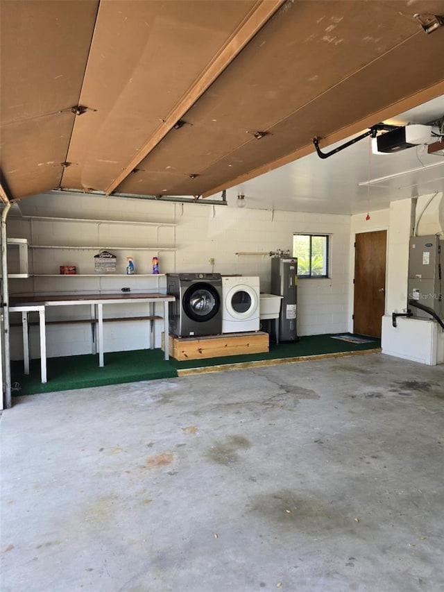 garage with a garage door opener, water heater, concrete block wall, and washing machine and clothes dryer