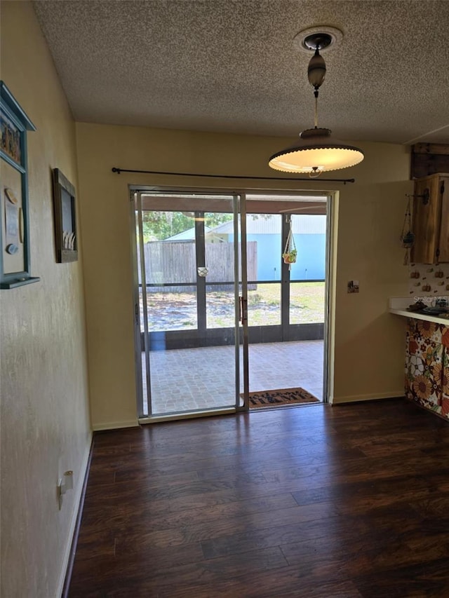 unfurnished dining area with baseboards, french doors, a textured ceiling, and dark wood-type flooring