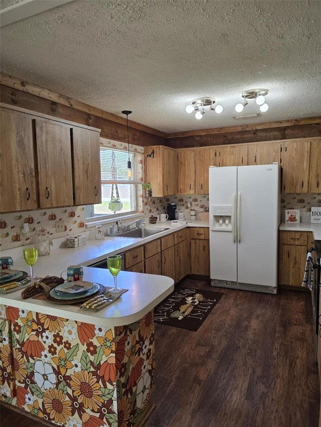 kitchen featuring dark wood-style flooring, a textured ceiling, a sink, light countertops, and white fridge with ice dispenser