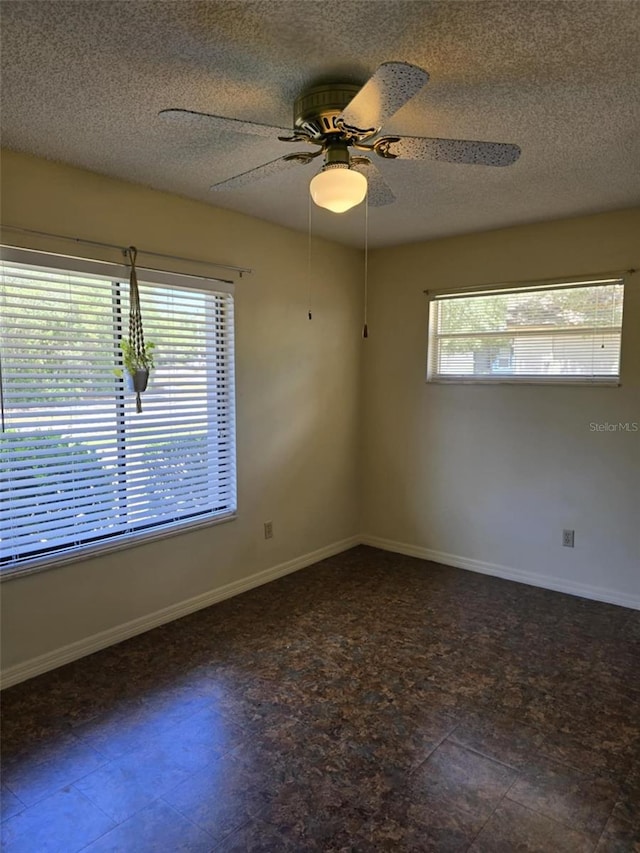 unfurnished room featuring baseboards, a ceiling fan, and a textured ceiling