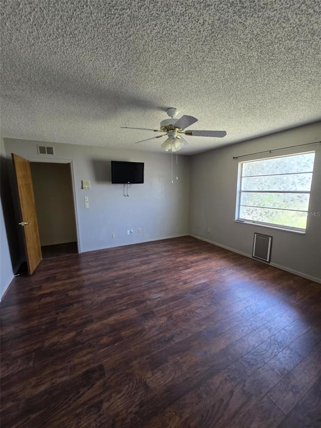 empty room featuring visible vents, a ceiling fan, a textured ceiling, and dark wood-type flooring