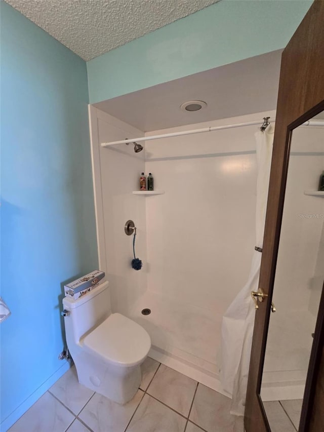 full bath featuring toilet, a textured ceiling, and a shower with shower curtain
