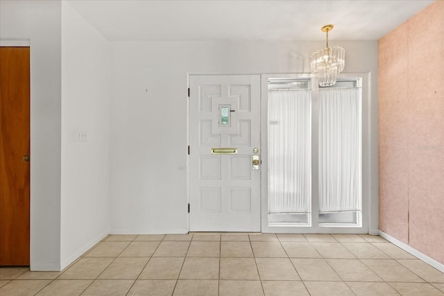 foyer entrance with baseboards, a chandelier, and light tile patterned floors