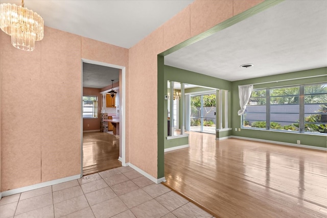 spare room with an inviting chandelier, baseboards, and visible vents