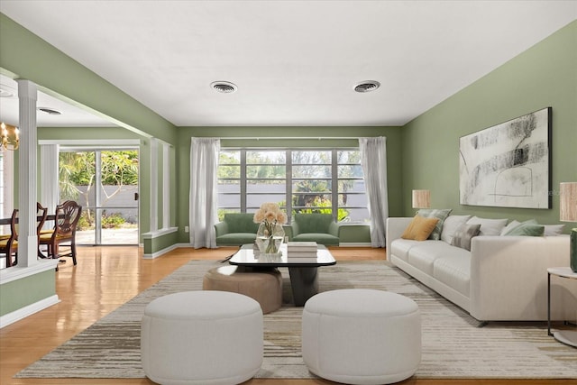living room with baseboards, visible vents, and wood finished floors