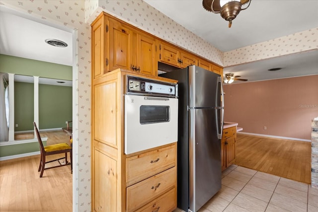 kitchen with visible vents, freestanding refrigerator, oven, light wood-style floors, and wallpapered walls