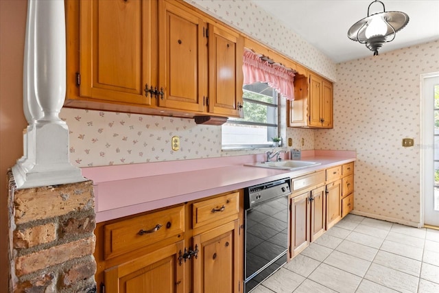 kitchen with a sink, light countertops, black dishwasher, and wallpapered walls