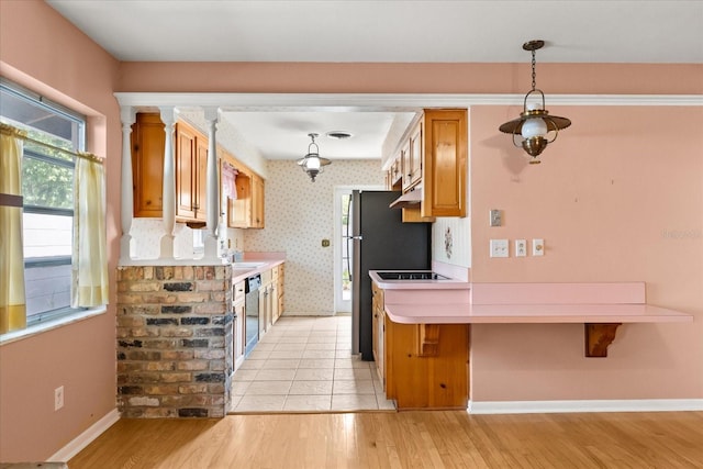 kitchen featuring brown cabinetry, light countertops, baseboards, black appliances, and light wood-style floors