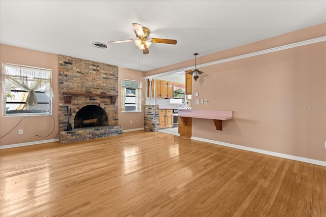 unfurnished living room with ceiling fan, light wood-style floors, a brick fireplace, baseboards, and visible vents