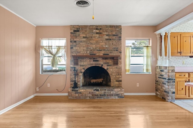 unfurnished living room with visible vents, light wood-style floors, a brick fireplace, and baseboards