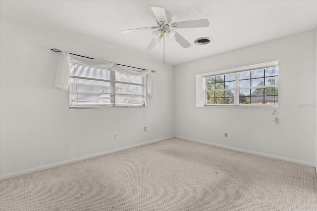 carpeted spare room with baseboards, a ceiling fan, and visible vents