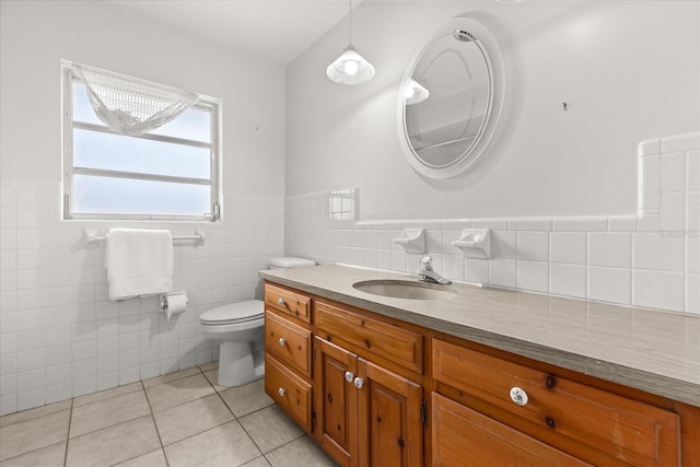 bathroom featuring wainscoting, tile patterned flooring, vanity, toilet, and tile walls
