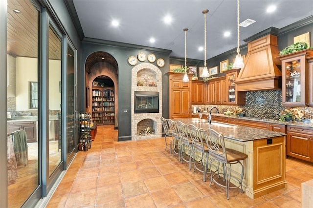 9730 Lounsberry Cir, Golden Oak, FL 32836 - kitchen with a sink, dark stone countertops, a fireplace, crown molding, and brown cabinetry