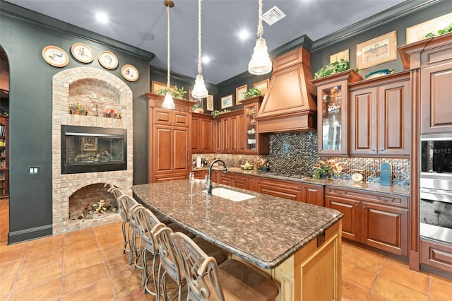 9730 Lounsberry Cir, Golden Oak, FL 32836 - kitchen featuring a sink, a fireplace, ornamental molding, tasteful backsplash, and a kitchen bar