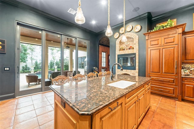9730 Lounsberry Cir, Golden Oak, FL 32836 - kitchen featuring a sink, crown molding, an island with sink, light tile patterned flooring, and brown cabinets