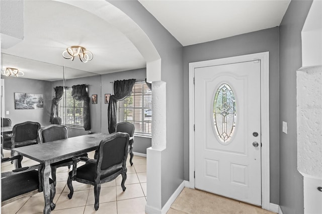 entrance foyer with arched walkways, baseboards, light tile patterned floors, and a wealth of natural light