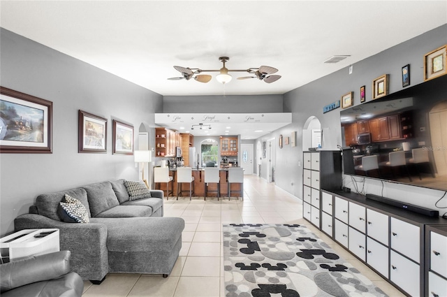 living area featuring visible vents, arched walkways, a ceiling fan, and light tile patterned flooring