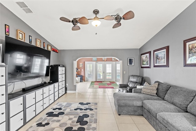 living room featuring visible vents, lofted ceiling, french doors, arched walkways, and light tile patterned floors