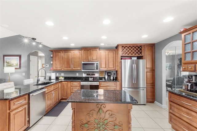 kitchen with a sink, appliances with stainless steel finishes, light tile patterned floors, and arched walkways