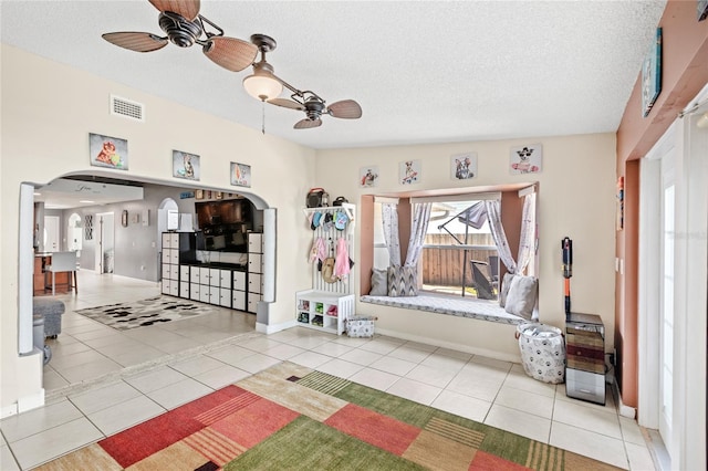 unfurnished living room featuring arched walkways, a ceiling fan, tile patterned floors, and visible vents