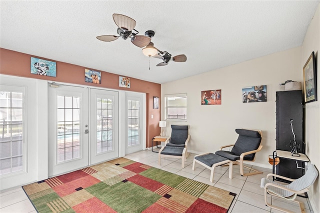 interior space featuring a textured ceiling, french doors, a ceiling fan, baseboards, and light tile patterned floors