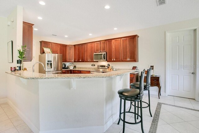 18108 Bellezza Dr, Orlando, FL 32820 - kitchen featuring a peninsula, light tile patterned flooring, a breakfast bar, and stainless steel appliances