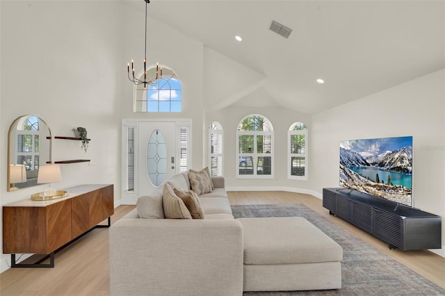 living area with light wood-style floors, a wealth of natural light, high vaulted ceiling, and visible vents