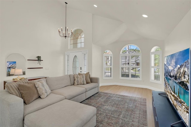 living room featuring high vaulted ceiling, recessed lighting, wood finished floors, and a notable chandelier