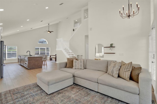 living room featuring light wood-style floors, high vaulted ceiling, recessed lighting, and stairs