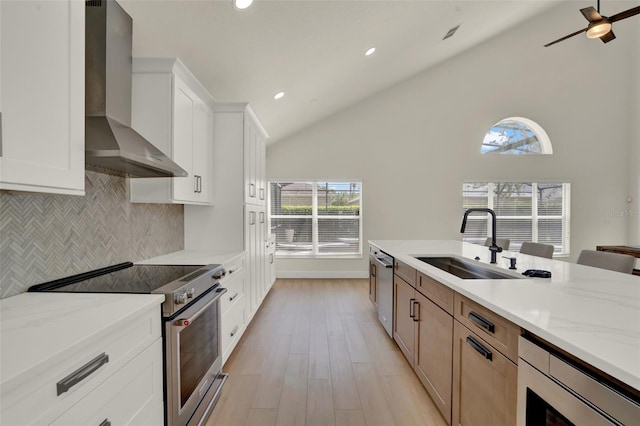 kitchen featuring decorative backsplash, light stone countertops, wall chimney exhaust hood, a sink, and stainless steel appliances